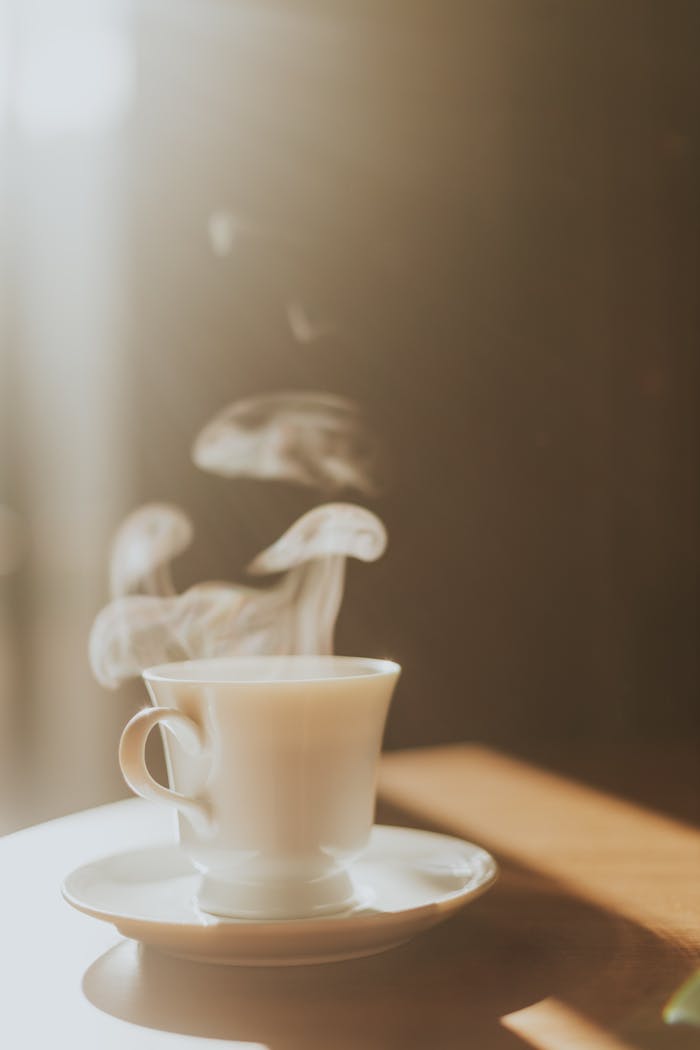 Warm steaming cup of coffee on a table with soft morning sunlight.